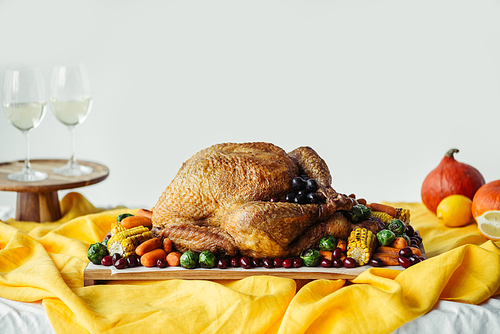 close up view of festive thanksgiving dinner table set with glasses of wine, roasted turkey and vegetables on tabletop with tablecloth