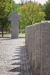 stone cross and identical tombs with lettering placed in row at graveyard