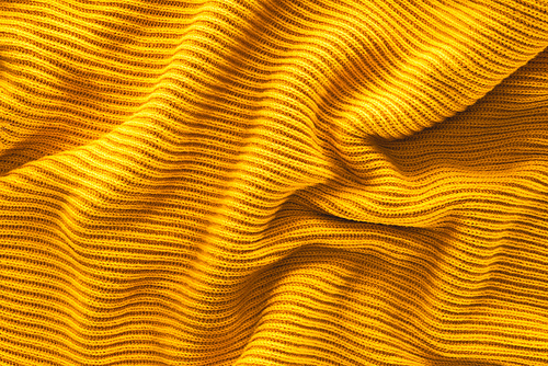 close up view of wavy yellow woolen fabric backdrop