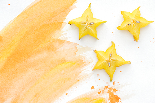 top view of star fruits on white surface with orange watercolor