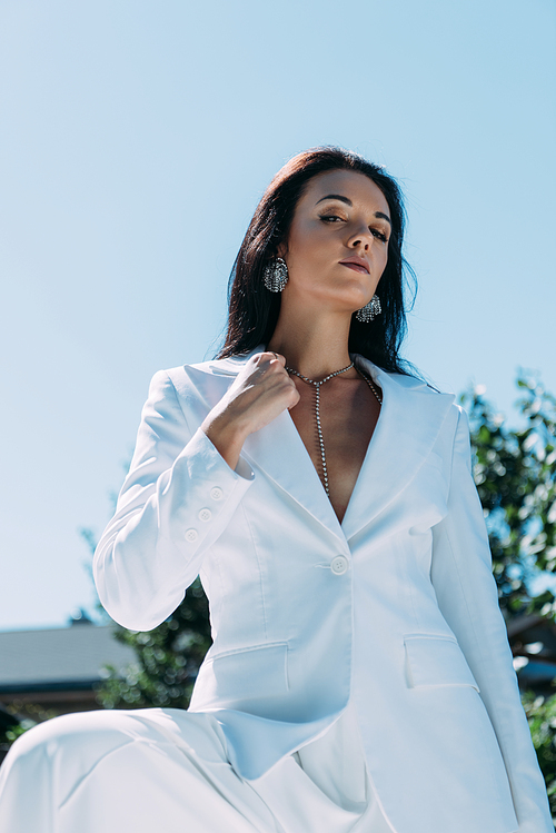 attractive woman in white suit posing and  outside
