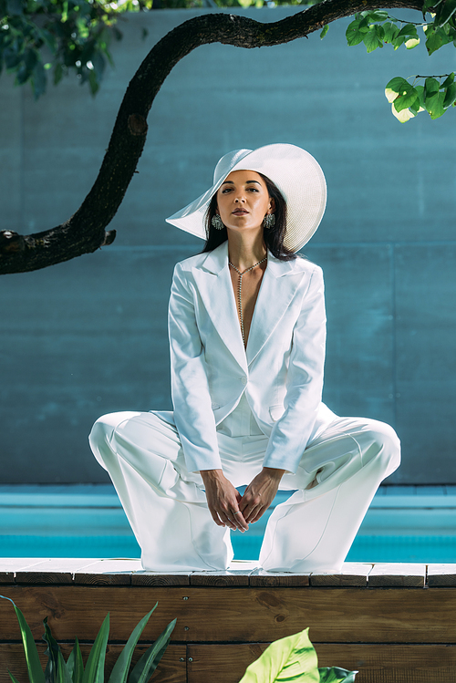 attractive woman in white suit and hat posing and  outside