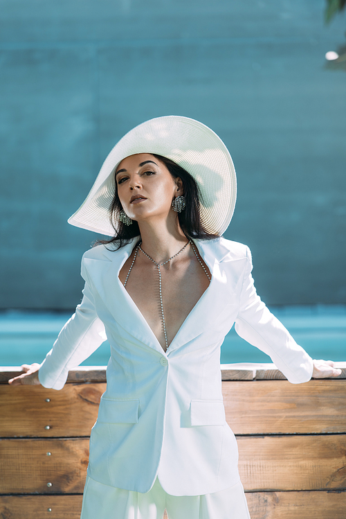 attractive woman in white suit and hat posing and  outside