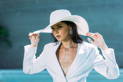 attractive woman in white suit and hat posing outside