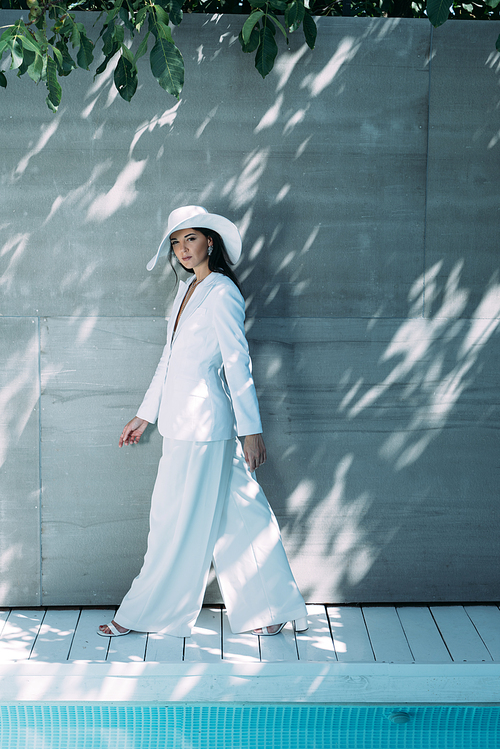 attractive woman in white suit and hat walking and  outside