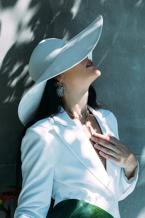 adult woman in white suit and hat posing outside