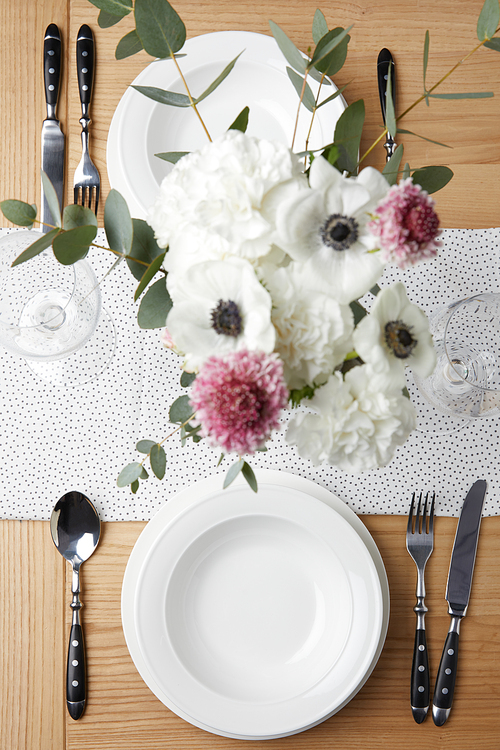 Festive table with cutlery and plates on table with flowers