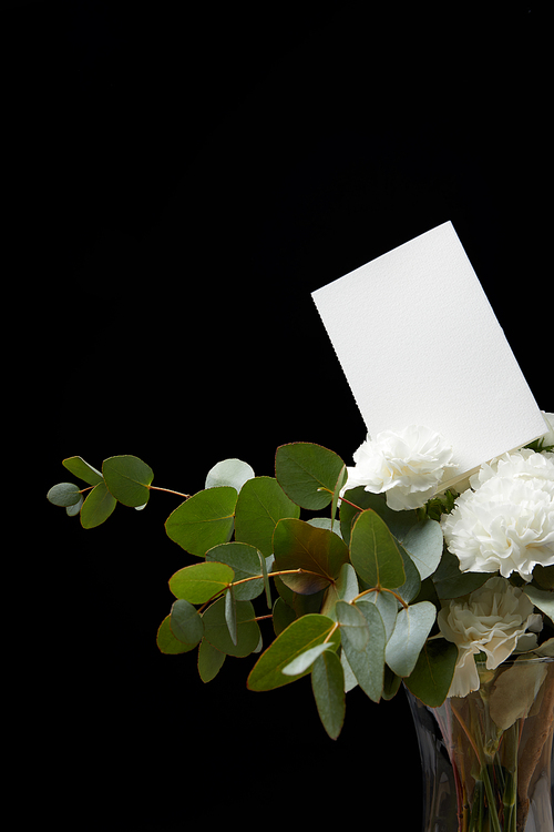 Vase with flower bouquet and empty card isolated on black