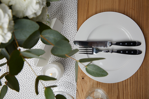 Table setting with cutlery on plate on table with flowers