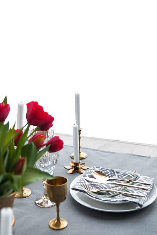 close up view of rustic table arrangement with red tulips, empty wine glasses, vintage silverware and plates