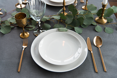 close up view of rustic table arrangement with eucalyptus, vintage cutlery and empty plates
