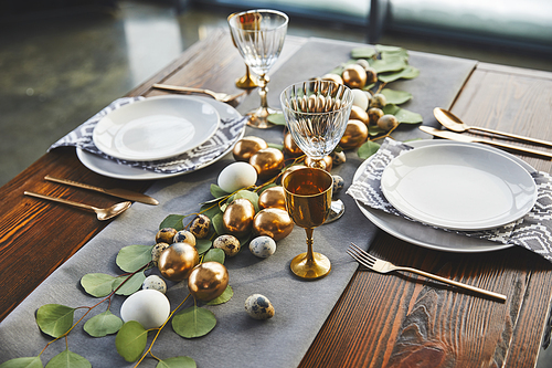 easter golden eggs, plates and glasses on table in restaurant