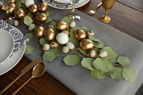 golden easter eggs on green leaves on festive table