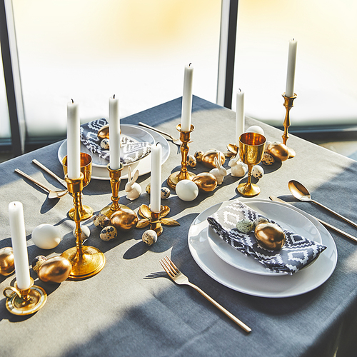 high angle view of easter eggs and candles on festive table with sunlight