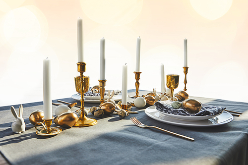 golden chicken eggs and candles on festive table