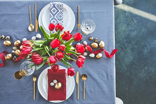 top view of bouquet of red tulips and easter eggs on festive table