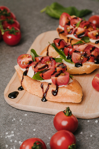 close-up view of tasty healthy bruschetta with tomatoes and balsamic on wooden board