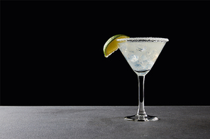 close up view of tasty margarita cocktail with lime and ice on tabletop on black