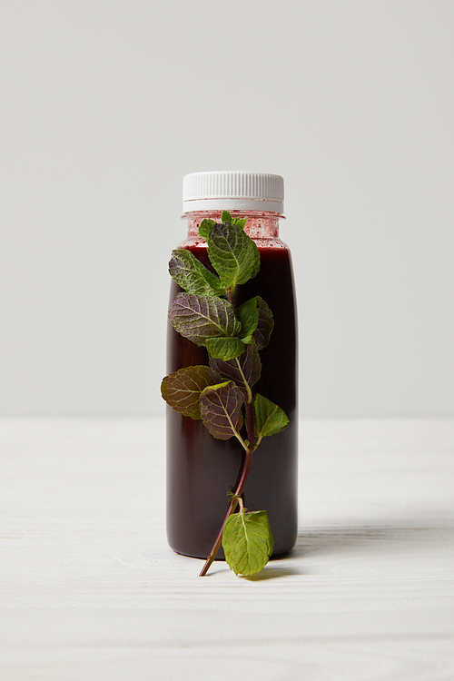 bottle of detox smoothie with mint on white wooden surface