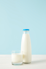 closeup view of bottle of milk and milk glass on blue background