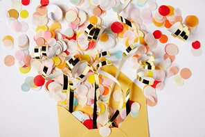 elevated view of confetti pieces and yellow envelope on white surface
