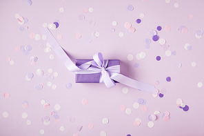 top view of one violet present box and confetti pieces on surface