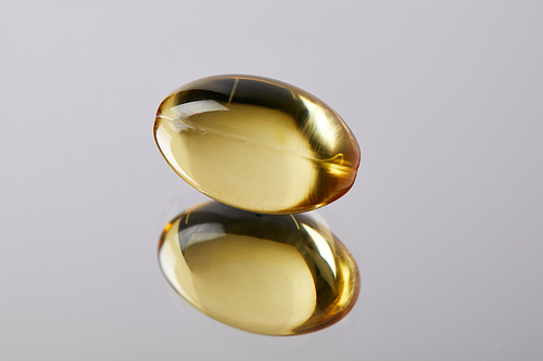 close-up shot of healthy omega fish hat supplement capsule on reflective surface
