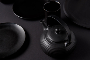 selective focus of 홍차pot, cup and plates on black table