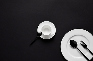 top view of plate, cup, black spoons and fork on black table