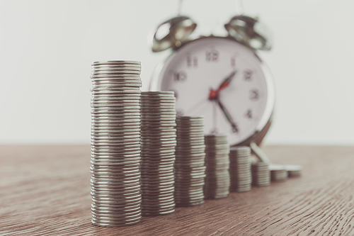 stacks of coins and alarm clock on tabletop, saving concept