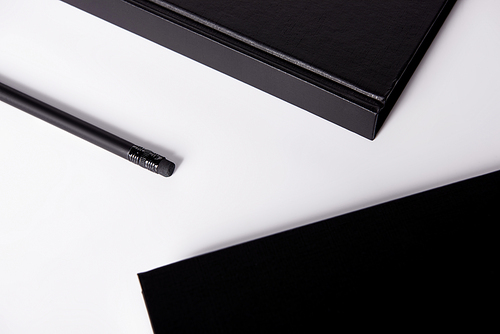 close-up shot of black notebooks with pencil on white surface for mockup
