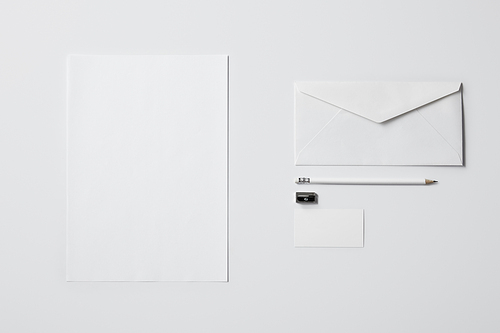 top view of business mockup with paper supplies and pencil on white surface for mockup