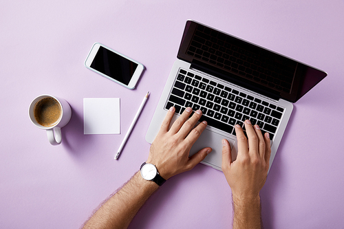 cropped shot of man using laptop at workplace on pink surface for mockup