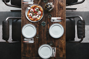 top view of delicious pizza on tray and table setting at restaurant