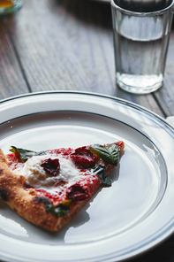 close-up shot of tasty pizza margherita on white plate with glass of water