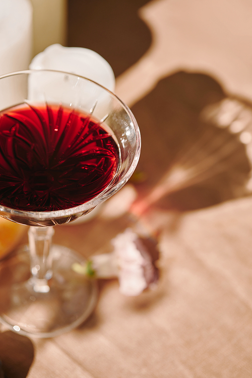 wineglass and candles on table in garden with shadow