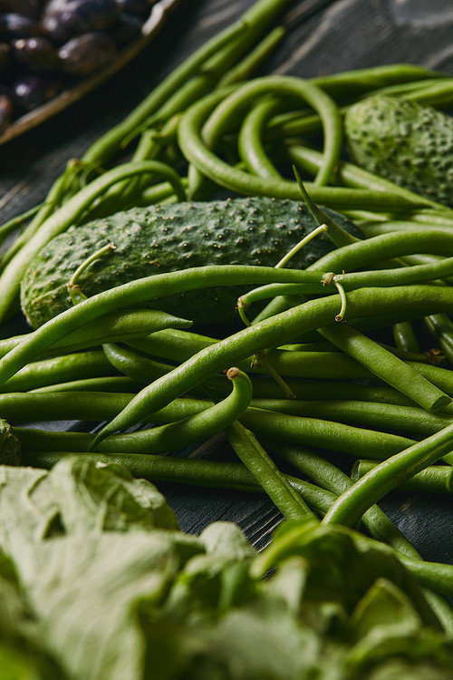 Cucumber and green beans on dark wooden table