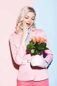 shocked woman in boxing glove holding bouquet on pink and blue background