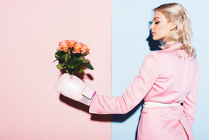 attractive woman in boxing glove holding bouquet on pink and blue background