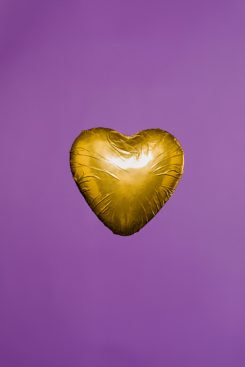 heart shaped candy in golden wrapper isolated on purple