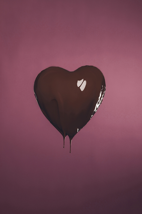 heart shaped candy with liquid chocolate isolated on pink