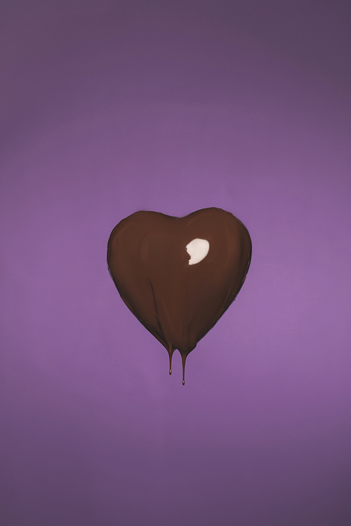 heart shaped candy with liquid chocolate isolated on purple