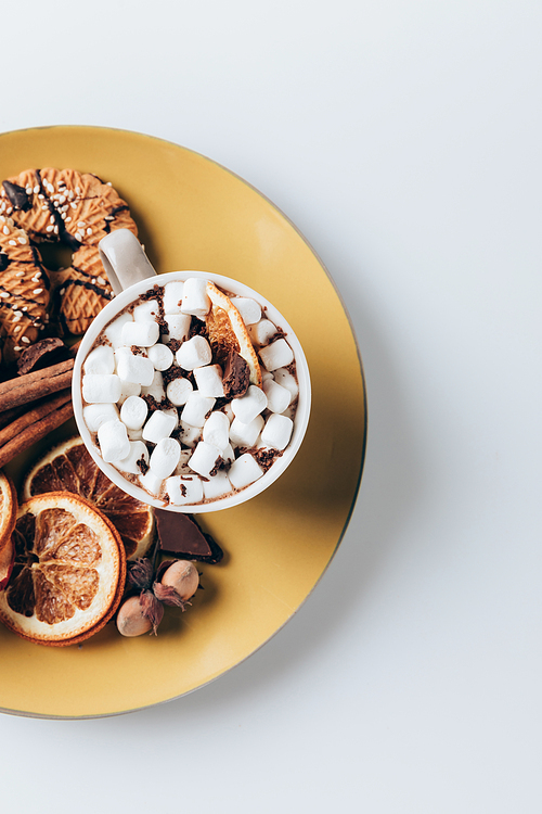 top view of plate with cookies and cup of hot cacao with marshmallows, on white