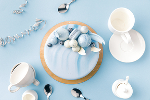 top view of blue cake with cups, plate and spoons isolated on blue