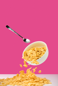 white bowl with healthy tasty corn flakes and spoon on pink
