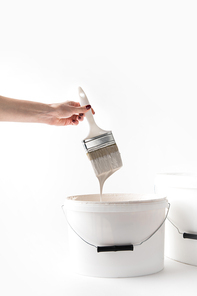 cropped image of girl holding brush with dripping white paint isolated on white