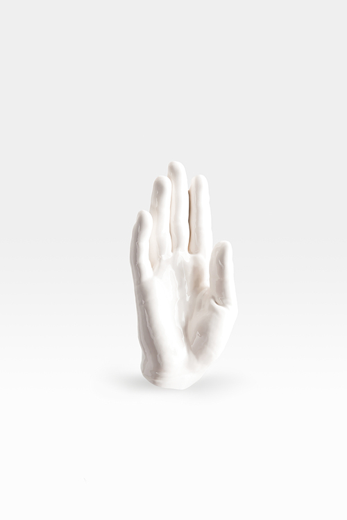 abstract sculpture in shape of human arm in white paint on white surface