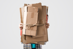 cropped shot of man holding pile of folded cardboard boxes isolated on grey, recycling concept