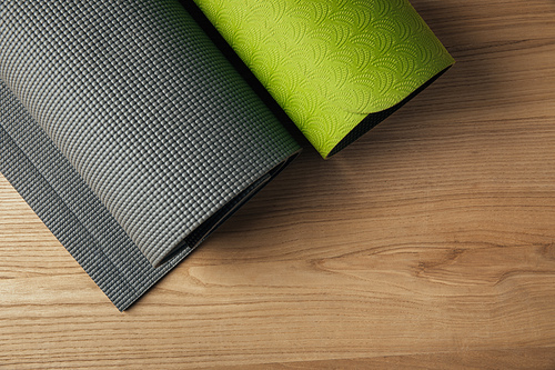 top view of two green and grey yoga mats on wooden floor