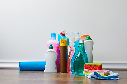 different bottles with domestic supplies for spring cleaning on wooden floor